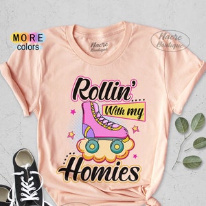 May include: Pink and white roller skate graphic on a peach colored t-shirt with the text "Rollin' With My Homies".