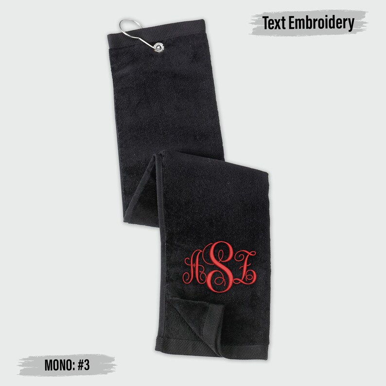 a black towel with a red monogram on it, and there is a text embroidery on the towel.
