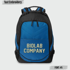 May include: A black and blue backpack featuring a chevron-stitched front panel and the embroidered text BIOLAB COMPANY in a light tan color. The bag includes a top handle, adjustable shoulder straps, and dual zipper closures on the main compartment.