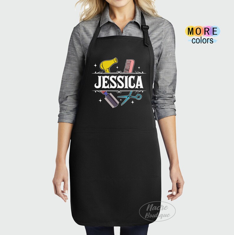 Puede incluir: Delantal negro con un bolsillo blanco y un dise&ntilde;o con un secador de pelo, un peine, unas tijeras y el nombre "JESSICA".