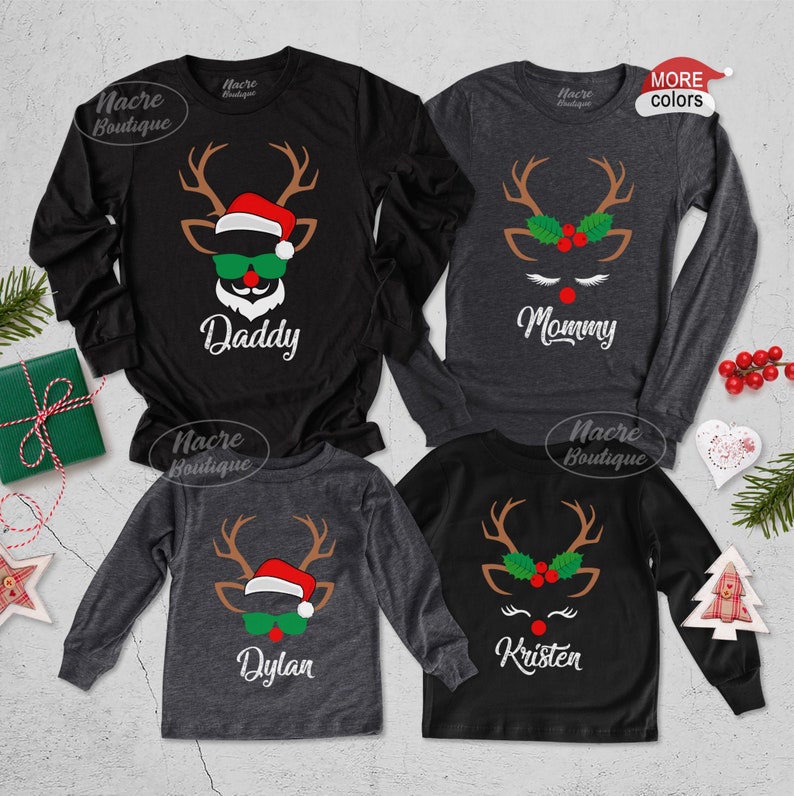 Pode incluir: Quatro camisas de Natal de manga comprida com desenhos de renas. As camisas s&atilde;o pretas e cinzentas, com as palavras "Daddy", "Mommy", "Dylan" e "Kristen" impressas sob as caras das renas. As renas t&ecirc;m chifres, &oacute;culos de sol e gorros de Pai Natal.