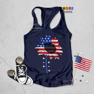May include: A navy blue tank top with a sunflower design. The sunflower is made up of the American flag colors, red, white, and blue. The sunflower has a black center and is surrounded by white stars. The tank top is a racerback style.