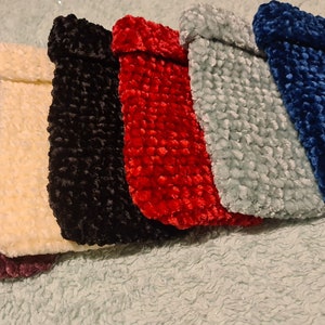 Op de afbeelding: Vijf gehaakte tasjes in verschillende kleuren: bordeauxrood, crème, zwart, rood en lichtblauw. De tasjes zijn gemaakt van een getextureerd garen en hebben een gevouwen bovenkant.