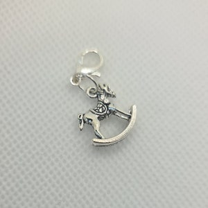 May include: Silver charm of a rocking horse with a loop for attaching to a bracelet or necklace.