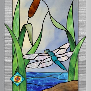 May include: Stained glass panel featuring a dragonfly in flight over water, with cattails and reeds. The dragonfly has a turquoise body and iridescent wings. The background is a mix of blue and white, with a textured silver frame.