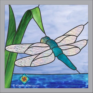 May include: A stained glass dragonfly with iridescent wings and a teal body is perched on a green leaf against a blue sky background. The dragonfly is flying over a blue body of water.