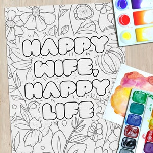 May include: A black and white coloring page with a floral background and the text "Happy Wife, Happy Life" in large, bold letters.