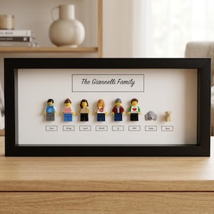 May include: A black rectangular shadow box frame containing six plastic minifigures and two small animal figures arranged in a row. Above the figures, the text reads The Giannelli Family. Below each figure, a small white label displays a name.