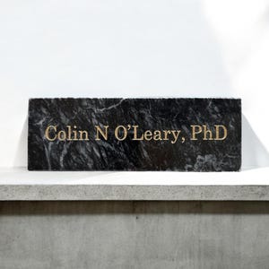 May include: A black marble plaque with gold lettering that reads "Colin N O'Leary, PhD".