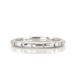 May include: A simple silver band ring with a textured design of small crescent moons around the entire band.