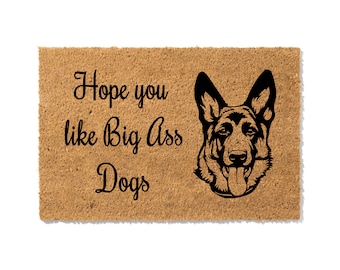 May include: Rectangular doormat with a German Shepherd dog illustration and the text "Hope you like Big Ass Dogs" in black. The mat is made of a light brown, textured material.