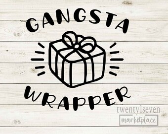 May include: Black and white graphic design on a wooden background. The text reads "GANSTA WRAPPER" with a gift box illustration in the center. The words "twenty1seven marketplace" are at the bottom.