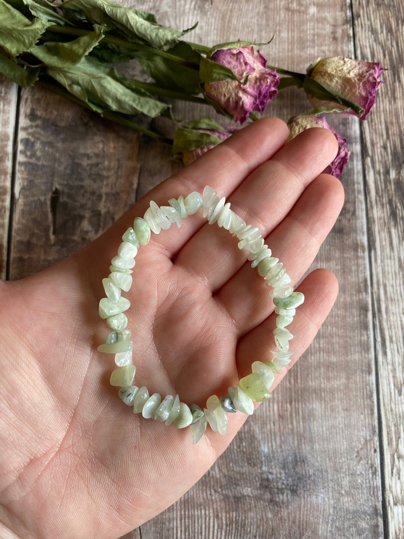 May include: A green jade chip bracelet with a light green color. The bracelet is made of small, irregular shaped chips of jade.