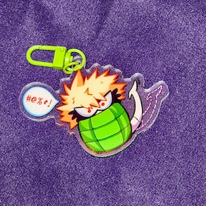 Puede incluir: Un llavero de un personaje de anime verde y amarillo con un bocadillo que dice "#%@!"