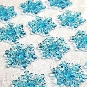 May include: Twelve small, light blue sugar snowflake decorations. The snowflakes are made of sugar and have a delicate, intricate design.