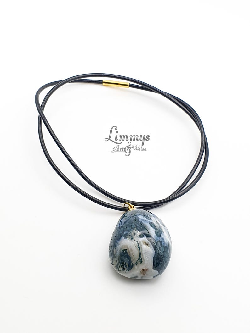 Puede incluir: Un collar de cuero negro con un colgante ovalado grande. El colgante es una mezcla de colores azul, blanco y verde. El collar tiene un cierre dorado. El texto "Limmys Art & Weise" est&aacute; en la imagen.