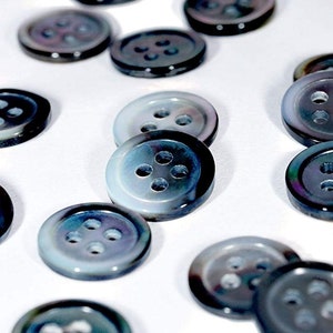 May include: A collection of 4-hole iridescent blue shell buttons. The buttons are round and have a smooth, polished finish.