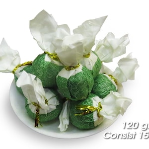 Pode incluir: Um prato branco com 15 bolas de chá verde embrulhadas em papel de seda branco e amarradas com uma fita dourada. Pacote de 120 gramas Contém 15 bolas de chá.