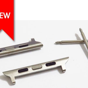 May include: Two silver watch band connectors and two silver watch band spring bars. The connectors have a silver finish and three black accents. The spring bars are straight and have a silver finish.