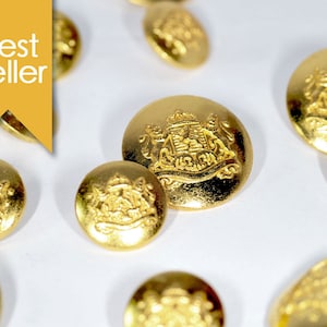 May include: A close-up of a group of gold-colored buttons with a raised design. The buttons feature a crest with a crown and two lions.