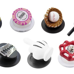 Puede incluir: Ocho objetos decorativos pequeños diferentes sobre bases circulares negras y blancas. Los objetos incluyen un bitcoin, una ficha de póquer, un guante de béisbol con una pelota, una raqueta de tenis con una pelota, una cuchilla de afeitar, una mano blanca, una válvula roja y una moneda de oro.