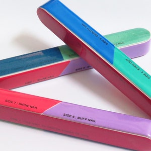 Peut inclure: Trois limes à ongles multicolores avec différents niveaux de grain. Les limes sont étiquetées avec les instructions suivantes : Côté 7 : Brillance des ongles, Côté 6 : Polissage des ongles, Côté 4 : Lissage, Côté 5 : Lissage.