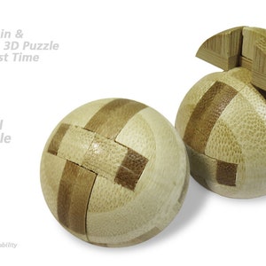 Puede incluir: Un rompecabezas de rompecabezas esférico 3D hecho de madera. El rompecabezas está en dos piezas, una de las cuales está parcialmente ensamblada. El rompecabezas tiene un diámetro de aproximadamente 4,5 cm.