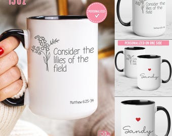 May include: White ceramic mug with a black handle and rim. The mug features the text "Consider the lilies of the field" with a floral illustration. The mug is 15 oz.