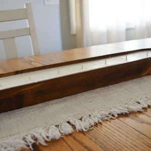 A side view of a brown dough bowl candle with cotton wicks unlit on a white table runner