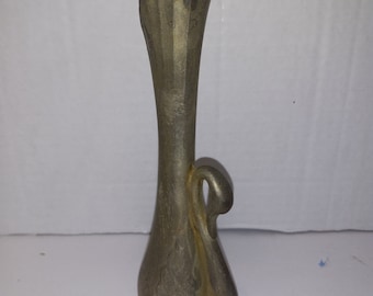 May include: A silver-colored metal vase with a swan design. The vase has a fluted top and a rounded base.