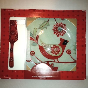 May include: A red and green glass serving platter with a cardinal bird design. The platter is packaged in a red box with white polka dots. The box also includes a red and white spatula.