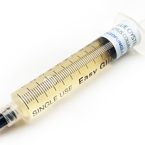 May include: A clear plastic syringe filled with a yellow liquid. The syringe is labelled "Easy Glic" and "Single Use". The label also includes the text "Blue Oyster, Lotus Column, LiquidFungi.com".