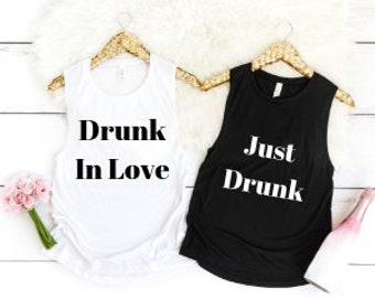 May include: Two sleeveless shirts, one white and one black, with text printed on the front. The white shirt says "Drunk in Love" and the black shirt says "Just Drunk".