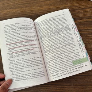 May include: A close-up of an open book with a yellow highlighter marking a passage about Mr. Darcy's character. The text reads, "And never allow yourself to be blinded by prejudice." The book is open to a page with a brown background and white text.