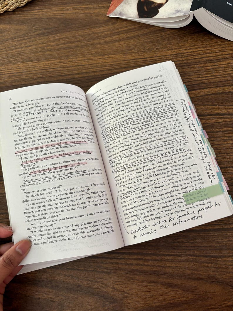 May include: A close-up of an open book with a yellow highlighter marking a passage about Mr. Darcy's character. The text reads, "And never allow yourself to be blinded by prejudice." The book is open to a page with a brown background and white text.