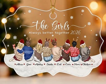 May include: A clear, scalloped-edge acrylic ornament featuring a group of eight illustrated figures wearing winter sweaters and hats. The text reads: the Girls Always better together 2026, with names Alexa, Gina, Ashley, Emilie, Cait, Cara, Nora, Chelsea.