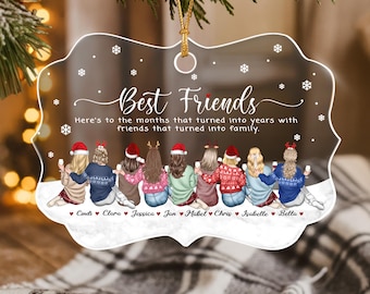 May include: A clear, scalloped-edge acrylic ornament featuring the text Best Friends and Here's to the months that turned into years with friends that turned into family. Eight illustrated figures in winter sweaters sit together with names below.