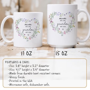 K&ouml;nnte beinhalten: Wei&szlig;e Keramikbecher mit floralem Herzdesign. Die Becher tragen die W&ouml;rter "Mom" und "Grandma" mit den Jahren 1999 und 2026. Der 11-oz-Becher ist 9,65 cm hoch und hat einen Durchmesser von 8,13 cm, der 15-oz-Becher ist 11,43 cm hoch und hat einen Durchmesser von 8,64 cm.