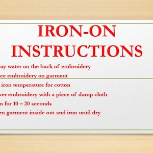 May include: A white sheet of paper with red text outlining instructions for ironing on an embroidery design. The instructions are: 1. Spray water on the back of embroidery, 2. Place embroidery on garment, 3. Set iron temperature for cotton, 4. Cover embroidery with a piece of damp cloth, 5. Iron for 10-20 seconds, 6. Turn garment inside out and iron until dry.