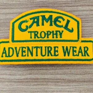 May include: Yellow and green embroidered patch with the text "Camel Trophy Adventure Wear".