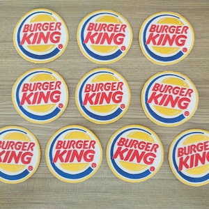Pode incluir: Dez  apoios de copo redondos, amarelos e azuis com o logotipo do Burger King em vermelho e branco.
