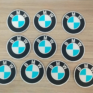 Peut inclure: Dix patchs ronds noirs et blancs avec le logo BMW en bleu et blanc. Les patchs sont disposés en trois rangées.