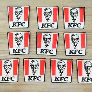 Op de afbeelding: Tien rode en witte patches met het KFC-logo en een cartoonafbeelding van Colonel Sanders. Elke patch heeft de tekst "KFC" in zwart.
