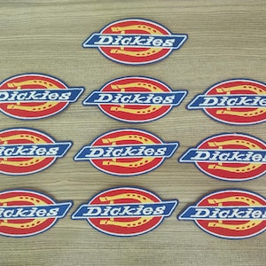 Puede incluir: Diez parches bordados azules y blancos con la palabra "Dickies" en letras blancas y un diseño de herradura amarilla.