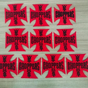 Puede incluir: Diez parches de hierro bordados rojos con un diseño de cruz negra y el texto "West Coast Choppers" en una fuente gótica.