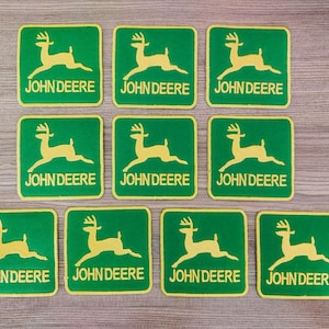 May include: Nine green and yellow iron-on patches with a stylised deer and the text "JOHN DEERE" on each.