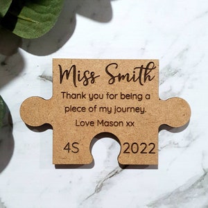 May include: A brown wooden jigsaw piece with the text "Miss Smith" and "Thank you for being a piece of my journey. Love Mason xx" and the numbers "4S" and "2022".