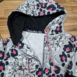 May include: A gray hooded sweatshirt with a black zipper and a white floral and leopard print. The text "Hahaha. N&ouml;." is printed on the inside of the hood.
