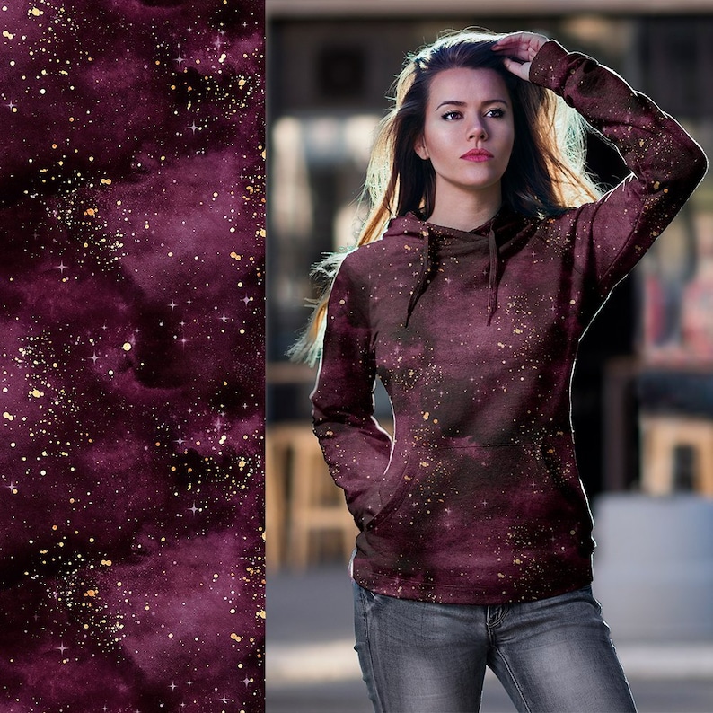 May include: A maroon hoodie with a galaxy print and gold glitter accents. The hoodie has a drawstring hood and a kangaroo pocket.