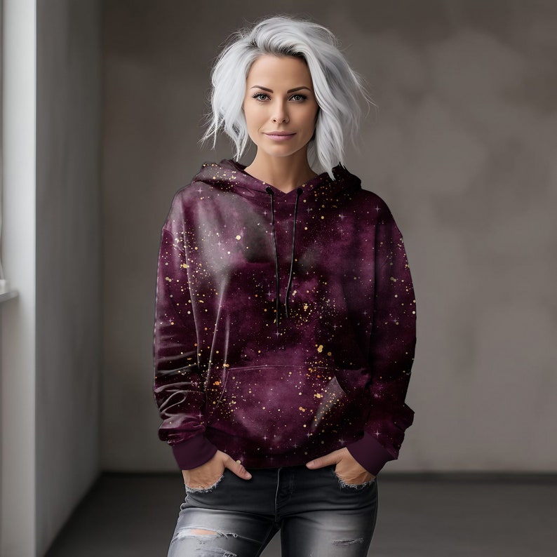 May include: A burgundy hoodie with a galaxy print and gold glitter accents. The hoodie has a drawstring hood and a kangaroo pocket.